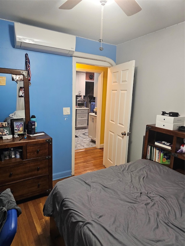 bedroom with a wall unit AC, hardwood / wood-style floors, and ceiling fan