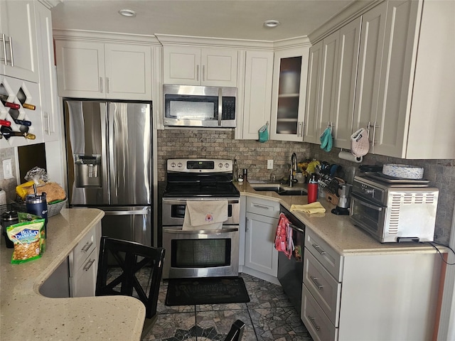 kitchen with sink, light stone counters, white cabinetry, stainless steel appliances, and tasteful backsplash