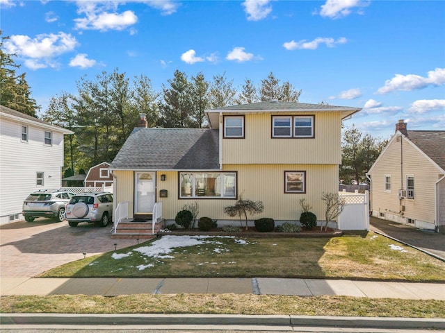 view of front of home featuring a front lawn, decorative driveway, and roof with shingles