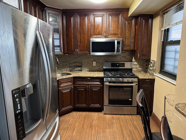 kitchen with sink, appliances with stainless steel finishes, dark brown cabinetry, and light hardwood / wood-style flooring