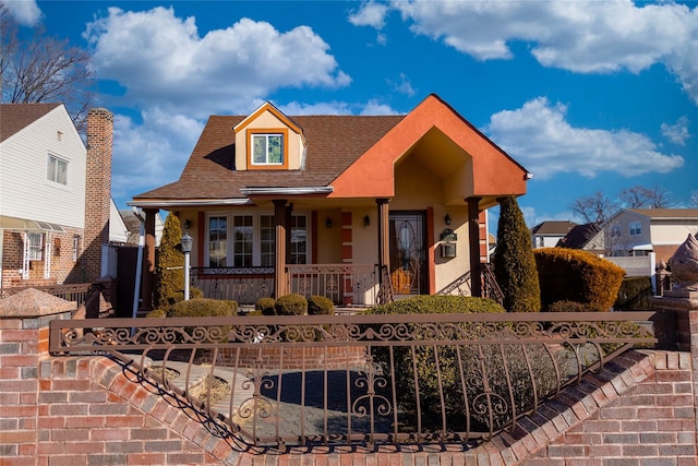 view of front facade featuring stucco siding, a porch, and a fenced front yard