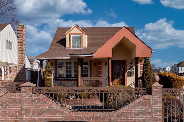 view of front of house featuring a fenced front yard, covered porch, and a shingled roof