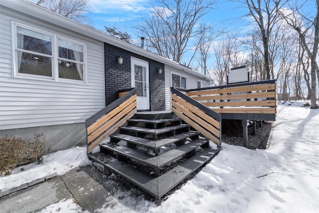 snow covered property entrance featuring brick siding