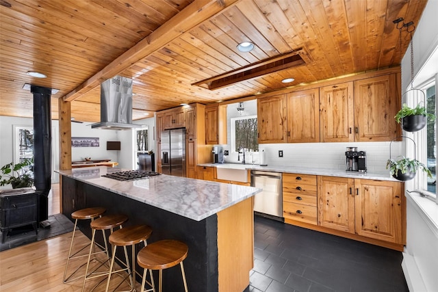 kitchen with a center island, island exhaust hood, stainless steel appliances, decorative backsplash, and a wood stove