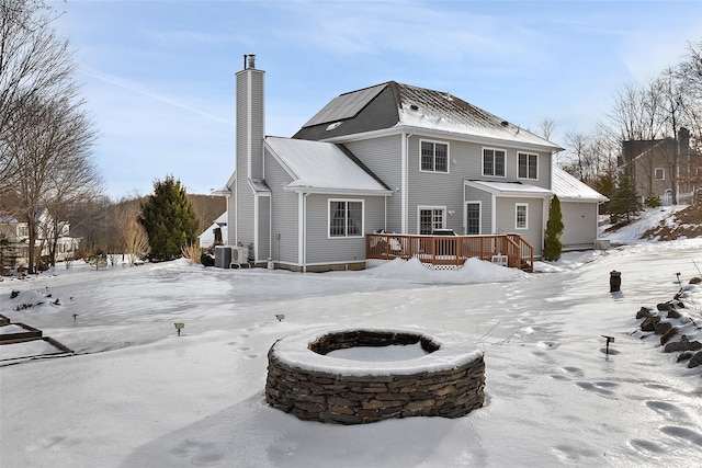 snow covered house featuring a chimney, a deck, and central air condition unit