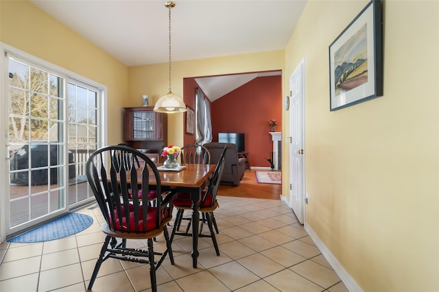 dining room featuring light tile patterned flooring, vaulted ceiling, and baseboards