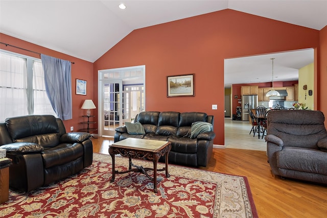 living room featuring high vaulted ceiling, french doors, plenty of natural light, and light wood-style floors