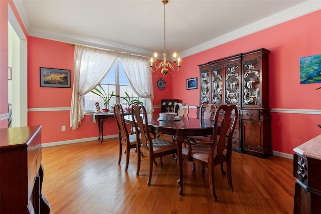 dining room featuring baseboards, an inviting chandelier, wood finished floors, and crown molding