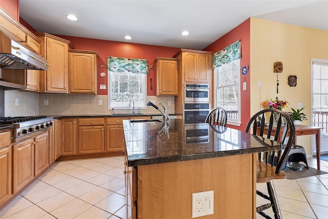 kitchen featuring appliances with stainless steel finishes, a sink, plenty of natural light, a breakfast bar, and recessed lighting