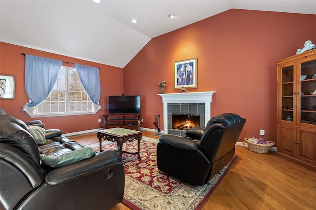 living area with wood finished floors, vaulted ceiling, a tile fireplace, and recessed lighting