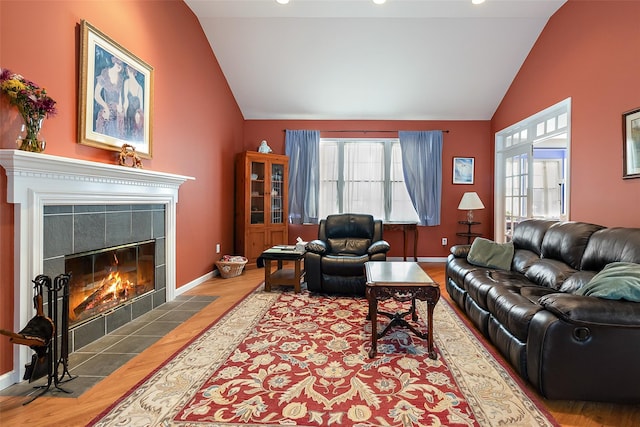 living room with vaulted ceiling, wood finished floors, a tiled fireplace, baseboards, and recessed lighting