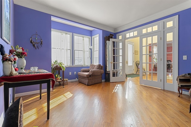 sitting room with french doors, wood finished floors, healthy amount of natural light, crown molding, and baseboards