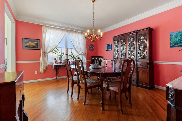 dining space with a chandelier, crown molding, wood finished floors, and baseboards