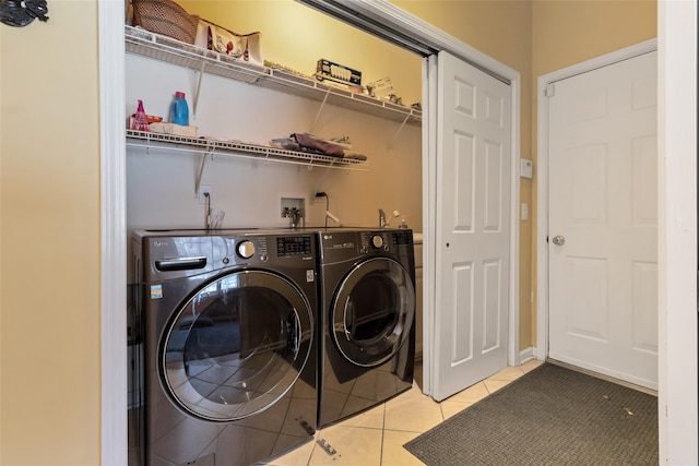 laundry area with washer and clothes dryer and light tile patterned floors
