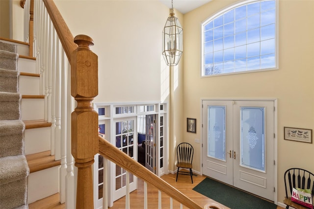 entrance foyer with french doors, stairway, wood finished floors, and a towering ceiling