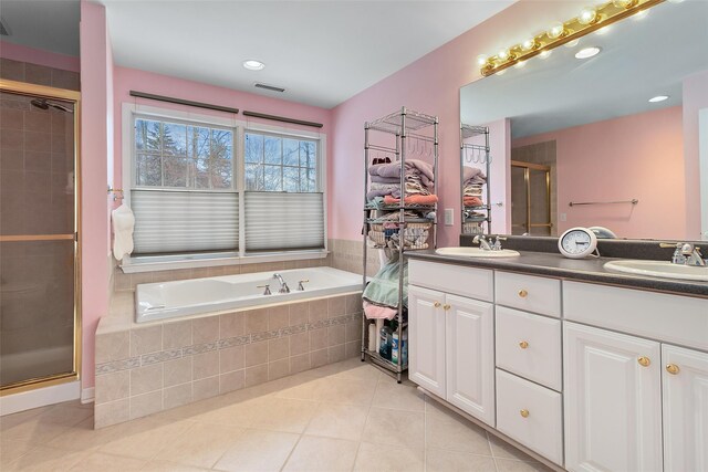 bathroom with tile patterned flooring, a shower stall, double vanity, a garden tub, and recessed lighting