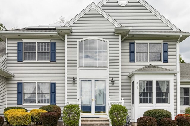 townhome / multi-family property featuring french doors and roof mounted solar panels