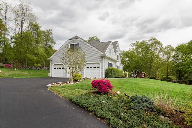 view of side of home featuring a lawn and asphalt driveway