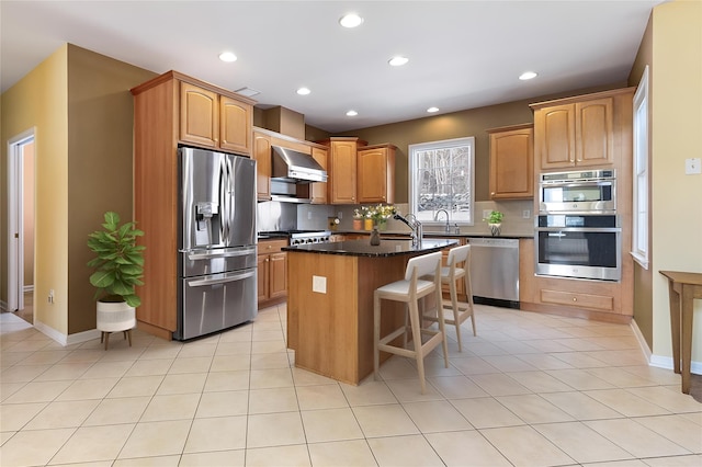 28 Teal Ln, Brewster, NY 10509 - kitchen featuring stainless steel appliances, wall chimney exhaust hood, a kitchen island with sink, tasteful backsplash, and a kitchen breakfast bar