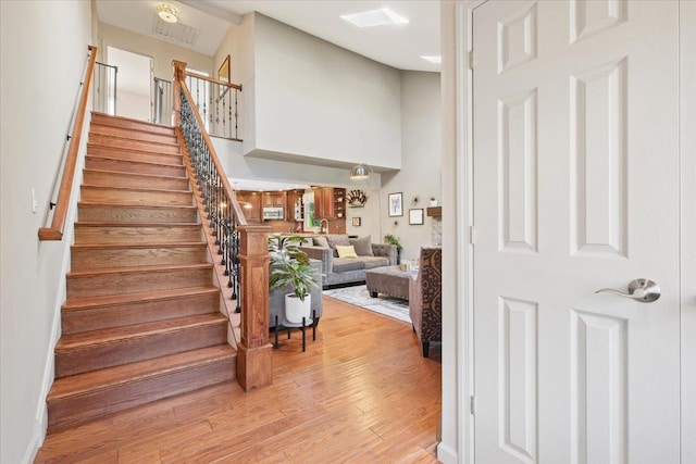 foyer entrance featuring a towering ceiling, light wood-style floors, and stairway