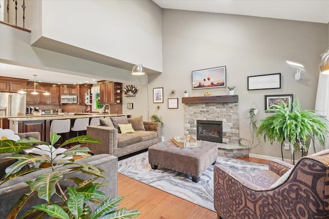 living room with a high ceiling, a fireplace, and light wood-style flooring