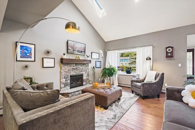 living room featuring high vaulted ceiling, a stone fireplace, a baseboard radiator, a skylight, and wood finished floors