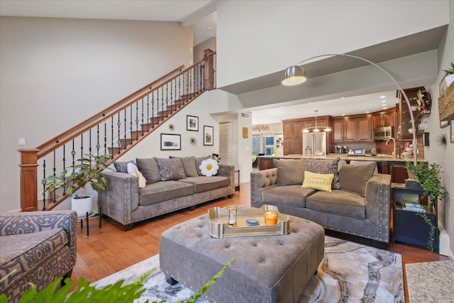 living area with light wood-type flooring, a high ceiling, and stairway