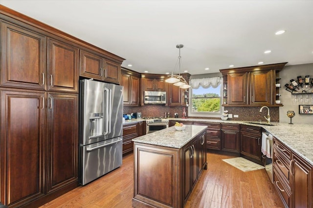 kitchen with open shelves, stainless steel appliances, hanging light fixtures, a kitchen island, and a sink