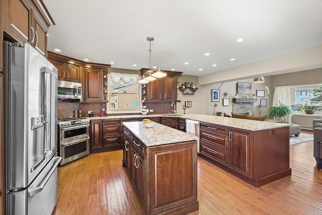 kitchen featuring a kitchen island, stainless steel appliances, a sink, and open floor plan