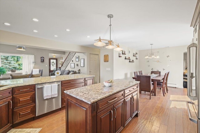 kitchen with light wood finished floors, open floor plan, a center island, decorative light fixtures, and stainless steel dishwasher