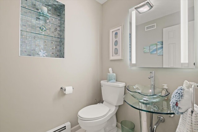 bathroom featuring baseboards, visible vents, toilet, a baseboard radiator, and a sink