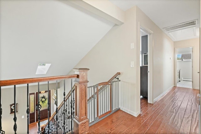 hall with attic access, baseboards, a baseboard radiator, wood finished floors, and an upstairs landing