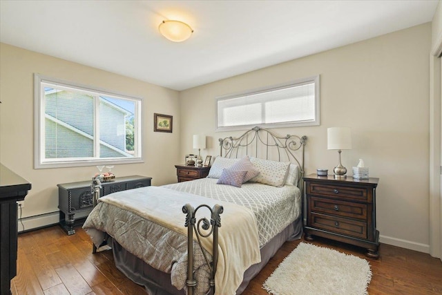 bedroom with dark wood-style floors, baseboard heating, and baseboards