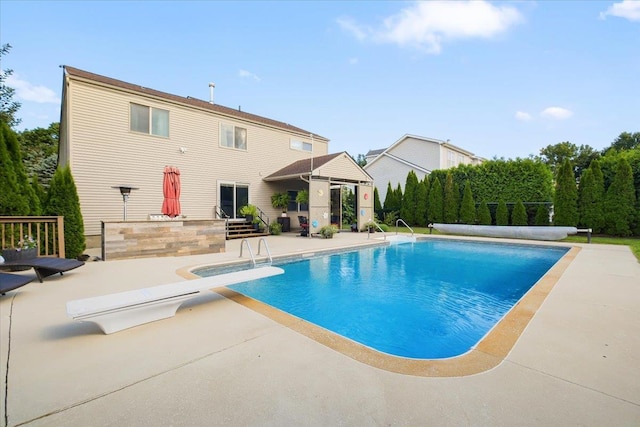 view of pool with a covered pool, a diving board, and a patio