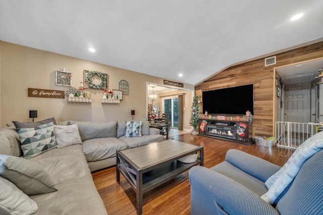 living area with attic access, visible vents, lofted ceiling, wood finished floors, and wood walls