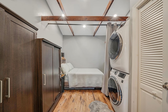 laundry room with stacked washer / drying machine, laundry area, and light wood-type flooring