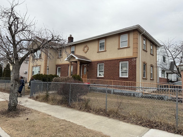 view of front of home featuring brick siding, a fenced front yard, a chimney, and stucco siding