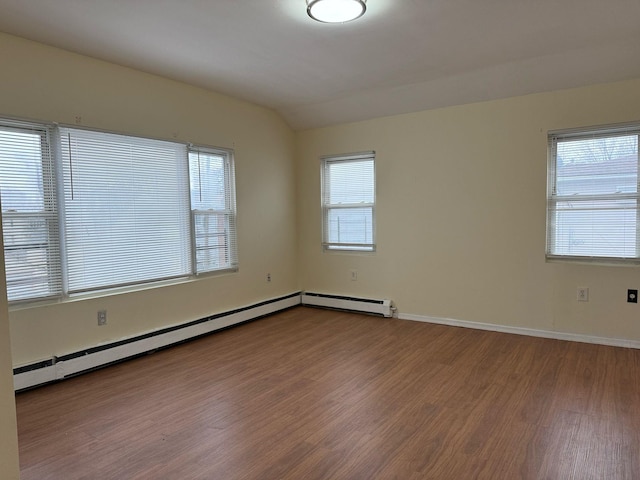 unfurnished room featuring a baseboard radiator, vaulted ceiling, baseboards, and wood finished floors