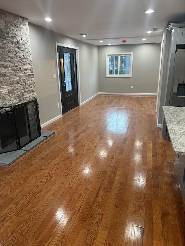 unfurnished living room featuring a stone fireplace and wood-type flooring