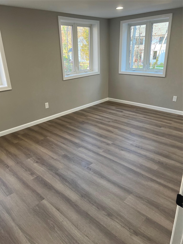 empty room with dark hardwood / wood-style flooring and plenty of natural light