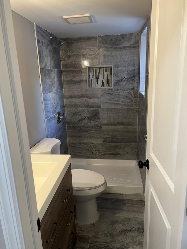 bathroom with vanity, a tile shower, toilet, and hardwood / wood-style floors