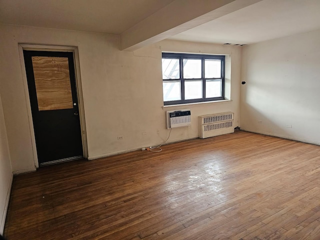 unfurnished room featuring beam ceiling, a wall unit AC, wood-type flooring, and radiator heating unit