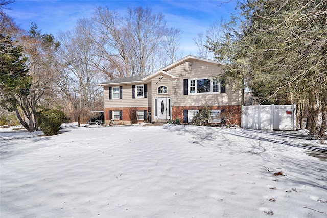 split foyer home featuring brick siding and fence