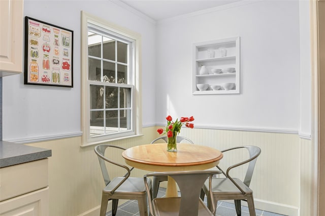 dining area with ornamental molding, a wealth of natural light, and wainscoting