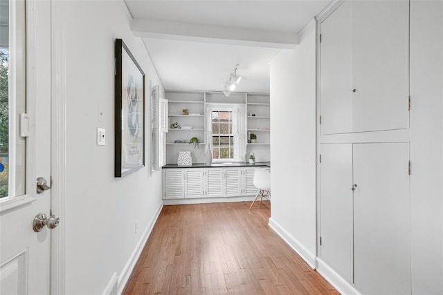 interior space with light wood-type flooring, rail lighting, and baseboards