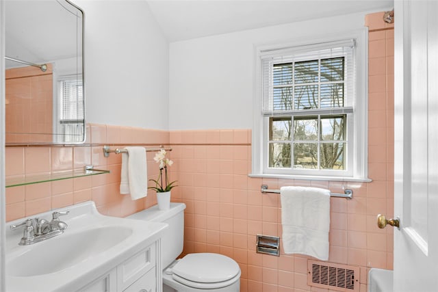 bathroom featuring visible vents, vanity, toilet, and tile walls