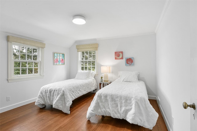 bedroom featuring lofted ceiling, baseboards, wood finished floors, and ornamental molding