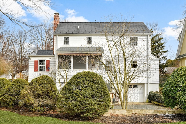 back of property with an attached garage and a chimney