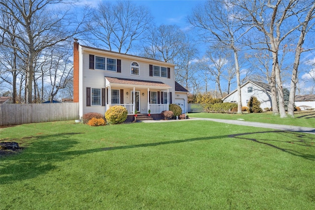 colonial-style house with a chimney, a porch, a front yard, fence, and a garage