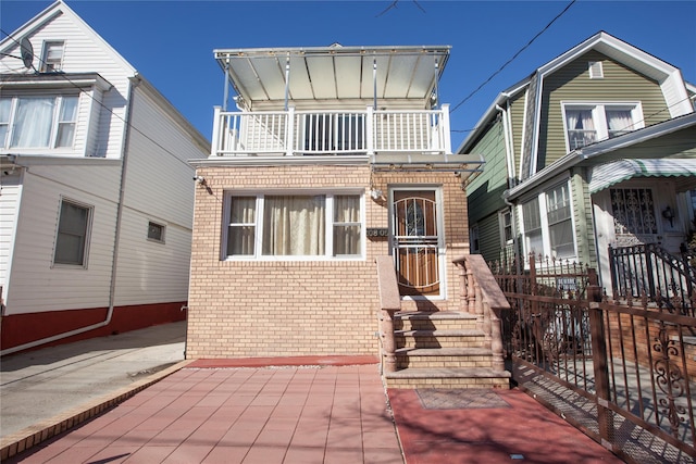 view of front of property featuring brick siding and a balcony